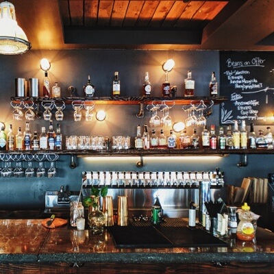 an image of a bar with a menu, lights and various alcohols displayed