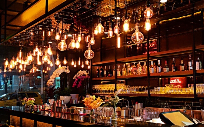 a picture of a bar with beautiful lights and decorative alcohol bottles behind