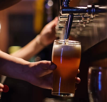 a bartender filling up a beer in a glass