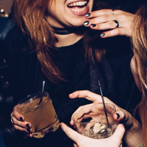 two women each holding a glass of alcoholic beverages in their hands